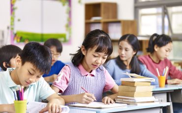 group of asian primary school boys and girls studying in class.