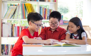 Asian young girl&boys reading books on desk and happiness feel at library in thier school